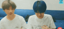 two men with blue hair are sitting next to each other on a couch .