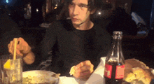 a man is sitting at a table with a coca cola bottle