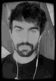 a black and white photo of a man with a beard wearing ear buds