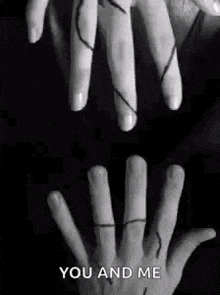 a black and white photo of two hands holding each other with a string between them .