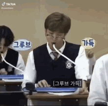 a group of students are sitting at desks in a classroom with microphones .