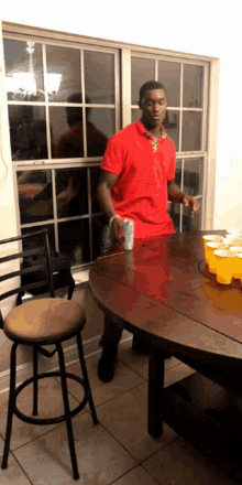 a man in a red shirt is standing at a table with cups