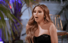 a woman in a strapless black dress is making a surprised face .