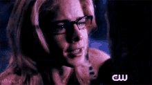 a close up of a woman wearing glasses and a cw logo