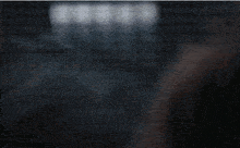 a woman wearing glasses is looking out of a window in the dark .