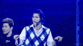 a man in a plaid vest is standing in front of a blue background with abema written on it