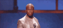 a man in a suit is standing in front of a microphone on a stage and making a funny face .