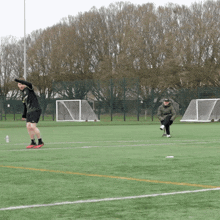 a man sits on the sidelines of a soccer field while another man kicks a ball
