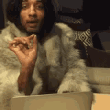 a woman in a fur coat is sitting in front of a laptop computer .