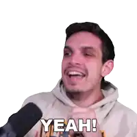 a man in a hoodie is smiling and says yeah in front of a microphone