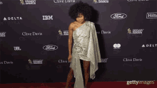 a woman stands on a red carpet sponsored by ford and ibm