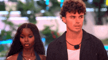 a man and a woman standing next to each other looking at something