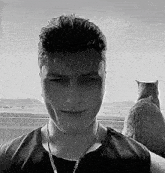 a man with a cat behind him looks at the camera
