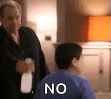 a man is spraying a child with a spray bottle while another man looks on .
