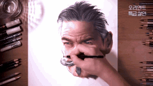 a drawing of a man with gray hair and a mustache is on a wooden table with colored pencils
