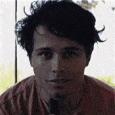 a young man in a red shirt is holding a microphone in his hand