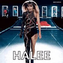 a woman is walking down a runway and the word halee is on the floor in front of her