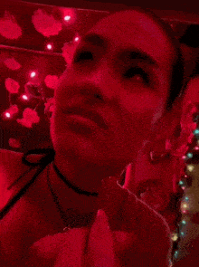 a close up of a woman 's face in a dark room with red lights .