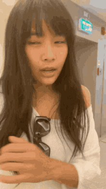 a woman wearing sunglasses and a white off the shoulder top looks at the camera