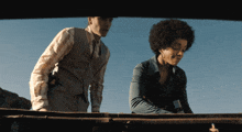 a man in a vest and a woman in a blue shirt are standing next to each other