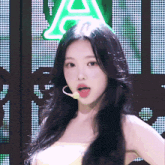 a woman with her tongue hanging out stands in front of a neon sign that says a