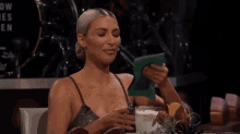 a woman in a dress is sitting at a table with a drink and looking at a piece of paper .
