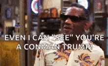 a man wearing sunglasses and a floral shirt is talking to another man in a bar .