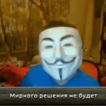 a man wearing a mask with a mustache is sitting in front of a computer screen that says мирного решения не будет