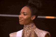 a woman with a bun on her head is wearing a gold and white dress