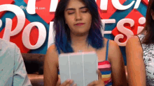 a woman with blue hair is holding a tablet in front of a poles sign