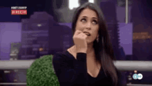 a woman in a black dress is sitting in front of a screen that says directo