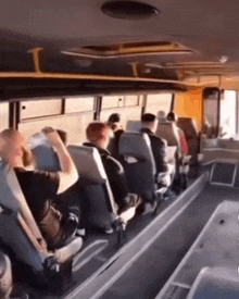 a group of people are sitting on a bus looking at something