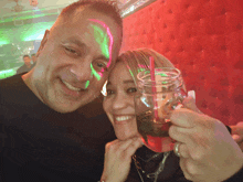 a man and a woman are posing for a picture and the woman is holding a mason jar with a straw in it