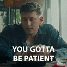 a man is sitting at a table with the words you gotta be patient on the bottom