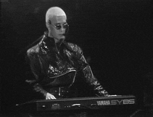 a man in a leather jacket is playing a yamaha sy85 keyboard