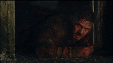 a man with blood on his face is laying on the ground in a dark room
