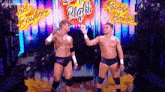 two wrestlers are standing next to each other on a stage .