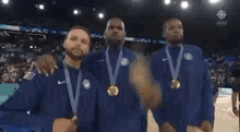a group of men are standing on a basketball court wearing medals .