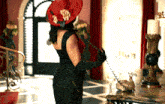 a woman in a black dress and a red hat is holding a telephone