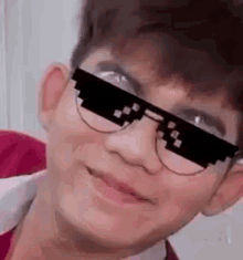 a young man wearing sunglasses and glasses is smiling for the camera .