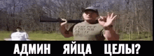 a man in a t-shirt is holding a gun and giving a peace sign .