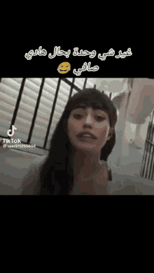 a woman is standing in front of a window with arabic writing on it