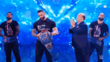 a man in a greatness on a different level more shirt is holding a wrestling championship belt