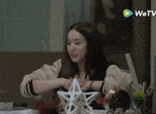 a woman is sitting at a table with a wetv logo in the background