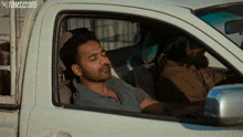 a man sleeping in a white truck with the year 2005 on the bottom