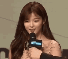 a woman is holding a microphone and smiling .