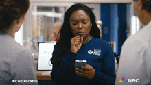 a woman wearing a chicago medical center uniform looks at her phone