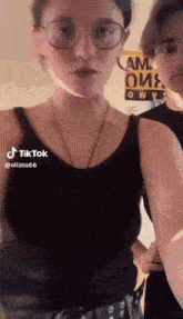 a woman in a black tank top and glasses is standing next to a man in a black shirt .