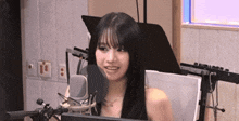 a woman is smiling in front of a microphone in a recording studio .