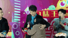 a man in a suit is hugging a woman in front of a sign that says tongplay